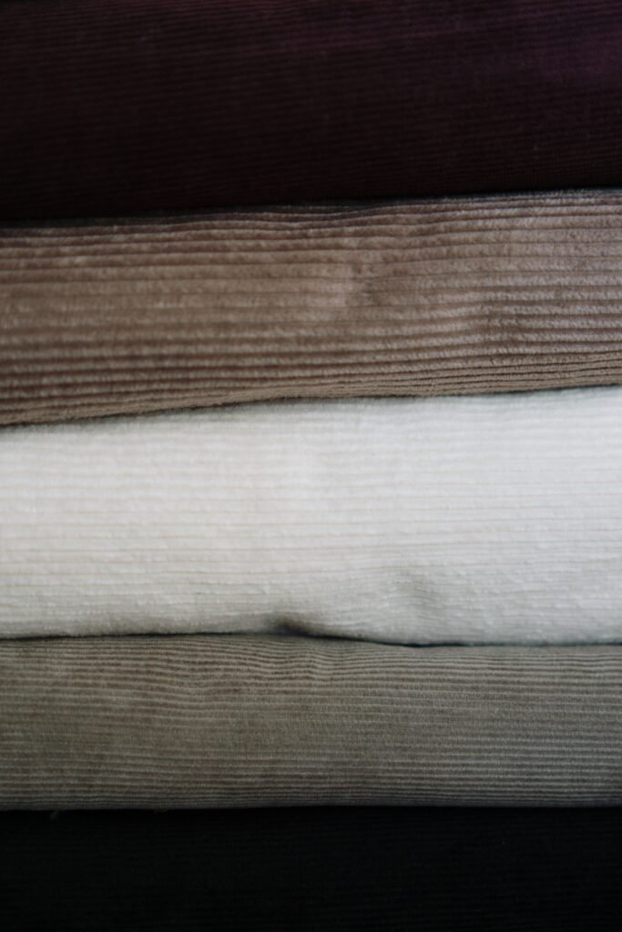 Close-up of stacked corduroy fabrics with textures in earthy tones.